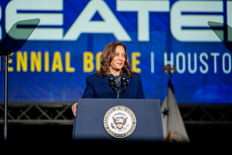 Kamala Harris smiles while standing at a podium