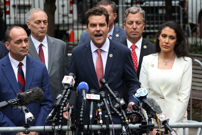 Matt Gaetz yelling in front of mics. Other Republican representatives including Anna Paulina Luna and Andy Ogles surround him.
