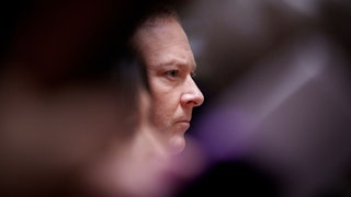 Lee Zeldin's face is seen in profile between the blurs of other objects.