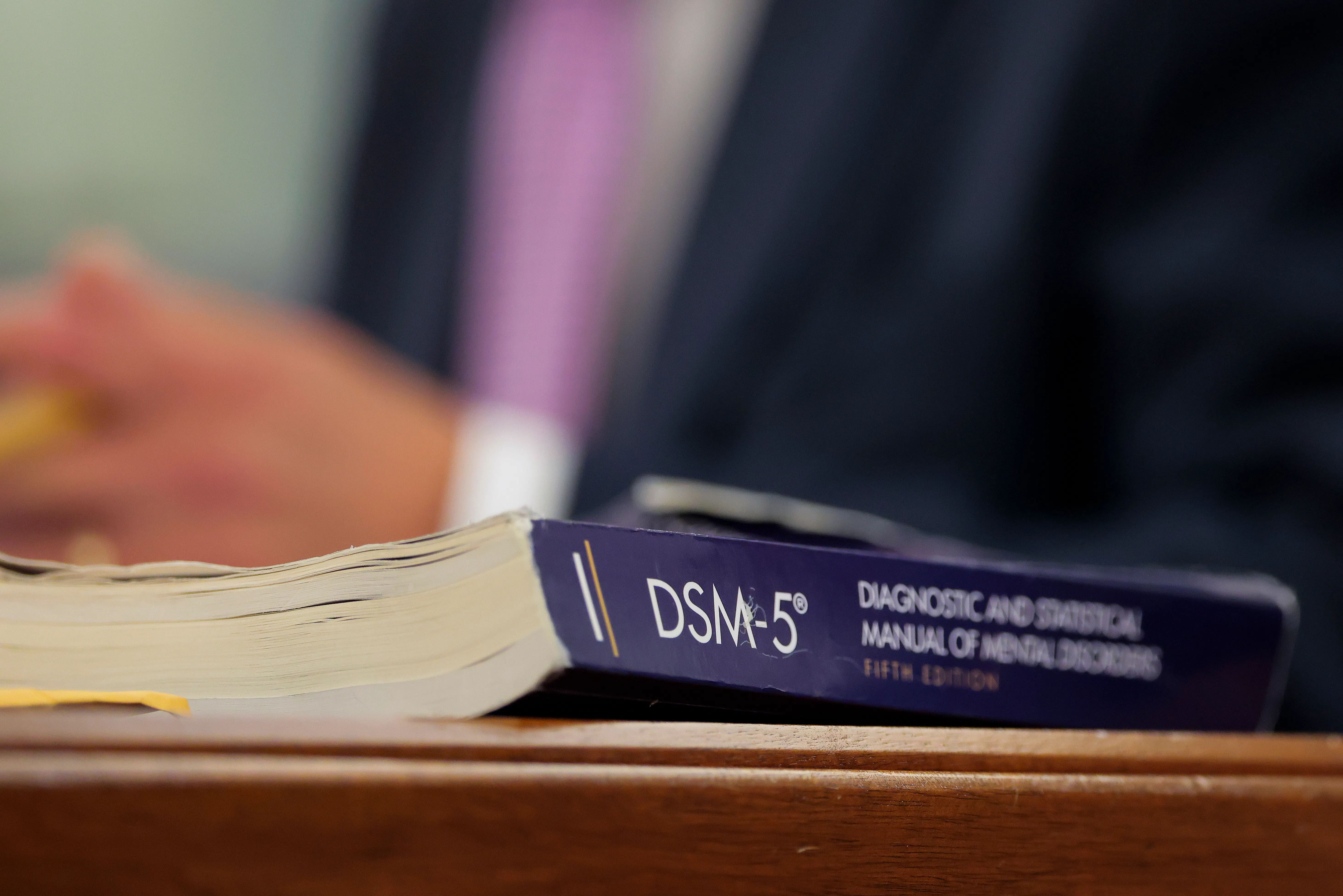 A DSM-5 book sits on a desk.