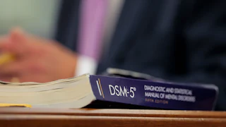 A DSM-5 book sits on a desk.