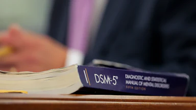 A DSM-5 book sits on a desk.
