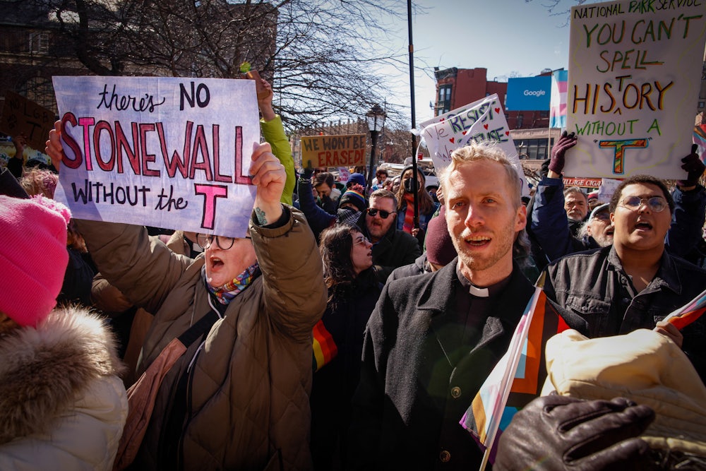 Demonstrators carrying signs, including one reading "There's no Stonewall without the T."