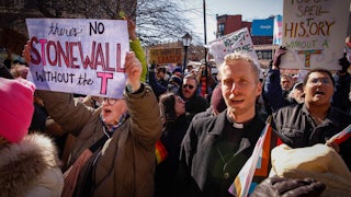 Demonstrators carrying signs, including one reading "There's no Stonewall without the T."