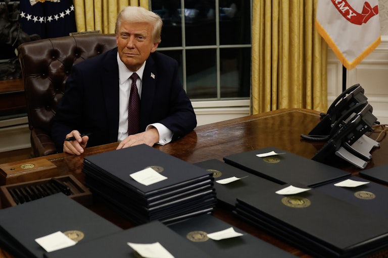 Donald Trump smiles and poses with his executive orders