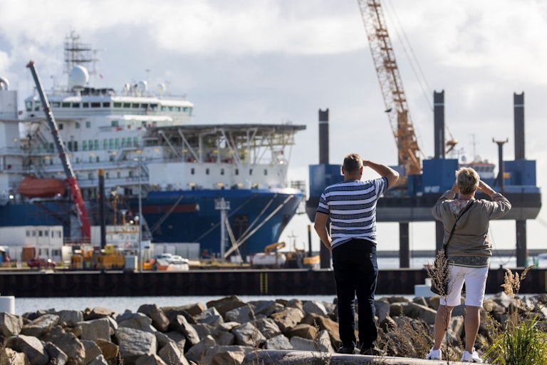 A couple takes pictures of a Russian pipe laying vessel on the island of Ruegen, Germany, as the ship waits to continue work on the Nord Stream 2 natural gas pipeline.