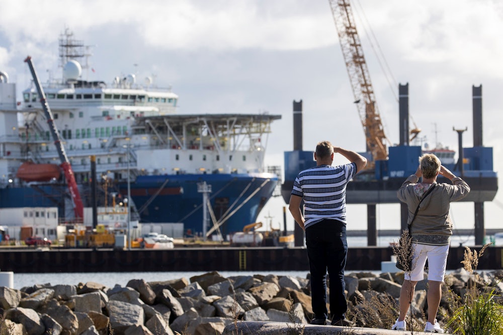 A couple takes pictures of a Russian pipe laying vessel on the island of Ruegen, Germany, as the ship waits to continue work on the Nord Stream 2 natural gas pipeline.