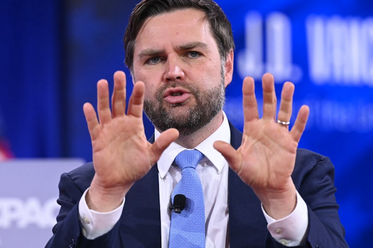 Vice President JD Vance holds up his hands while speaking onstage at CPAC