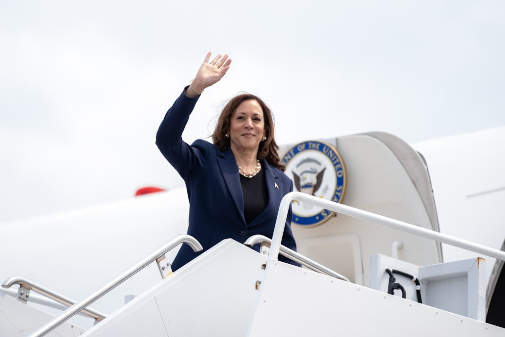 Kamala Harris standing and waving at the doorway to Air Force 2.