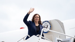 Kamala Harris standing and waving at the doorway to Air Force 2.