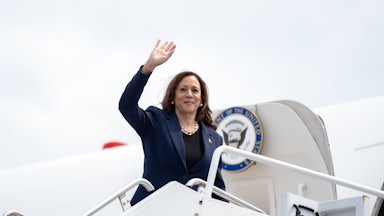 Kamala Harris standing and waving at the doorway to Air Force 2.
