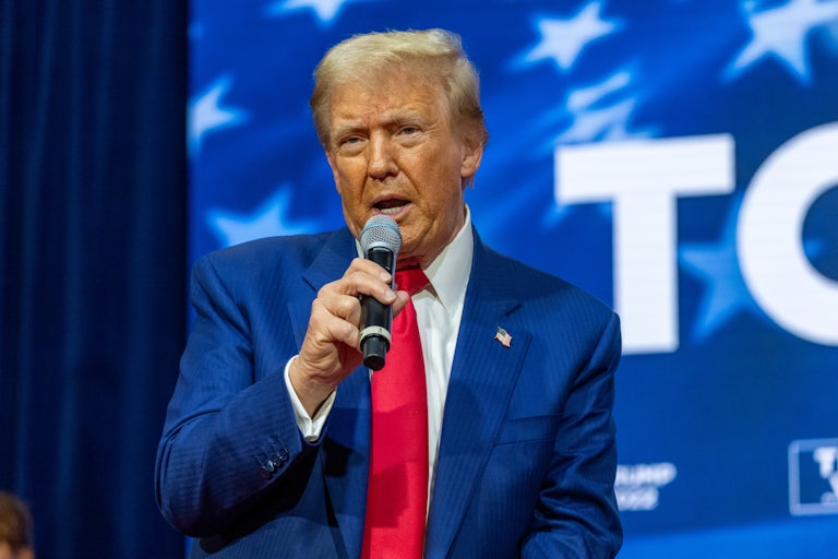 Donald Trump, seated, speaks with a mic in his hand
