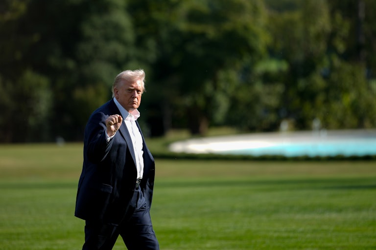 Donald Trump raises his fist while walking outside the White House