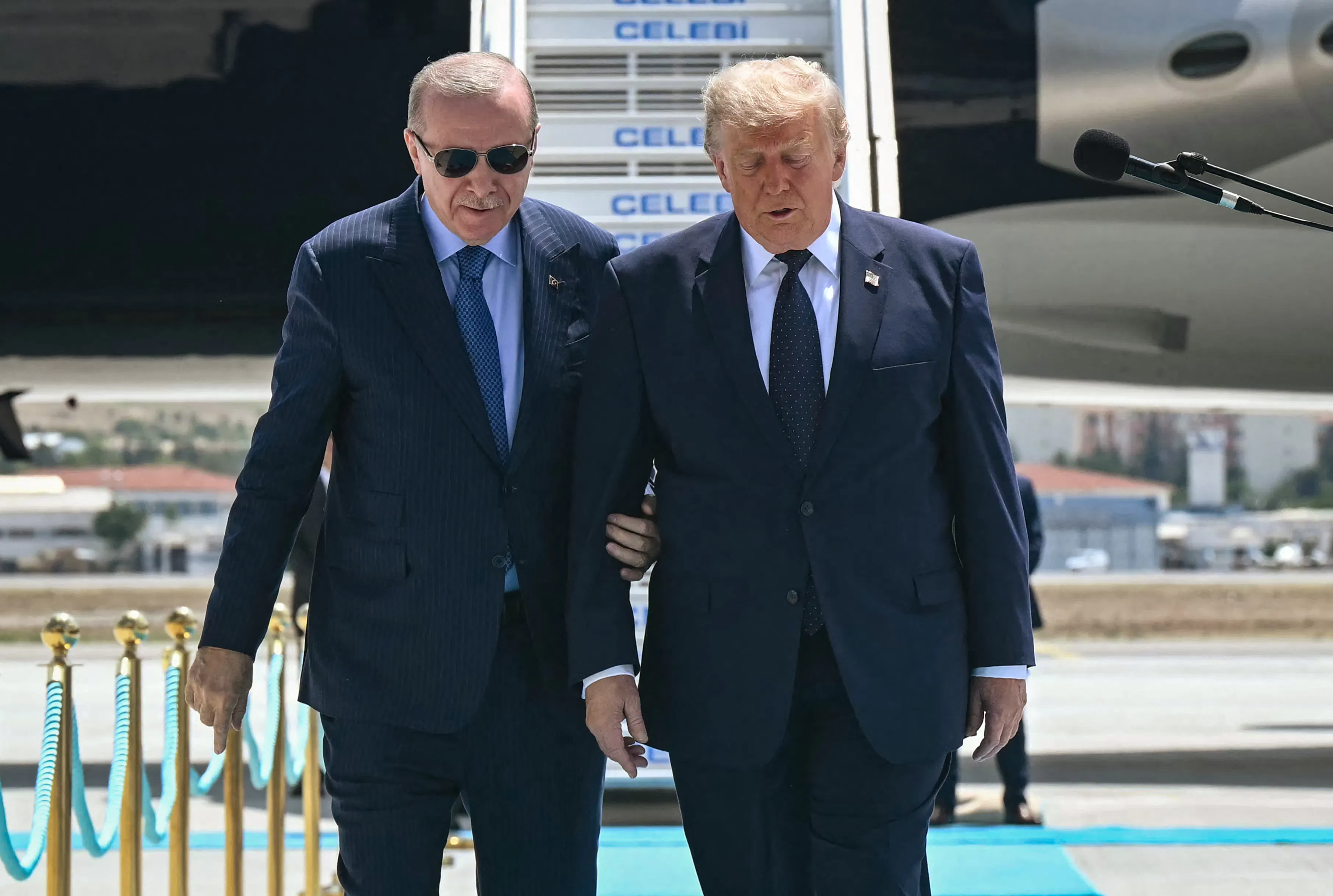 Turkish President Recep Tayyip Erdogan holds U.S. President Donald Trump's arm as if to keep him steady