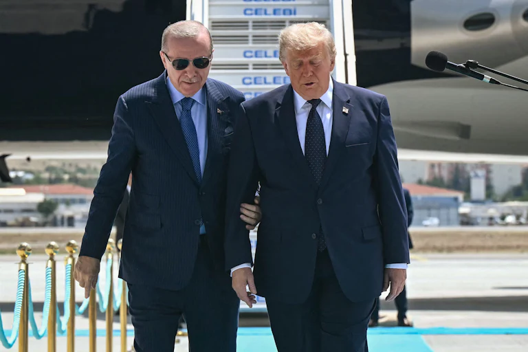 Turkish President Recep Tayyip Erdoğan holds President Donald Trump's arm as if to keep him steady.