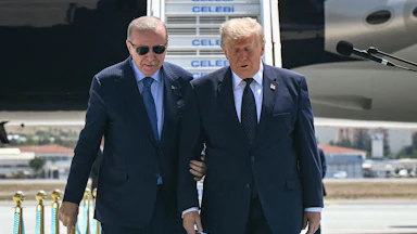 Turkish President Recep Tayyip Erdoğan holds President Donald Trump's arm as if to keep him steady.