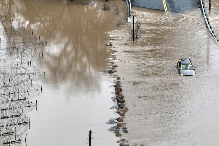 In an aerial view, a car is submerged in floodwater.