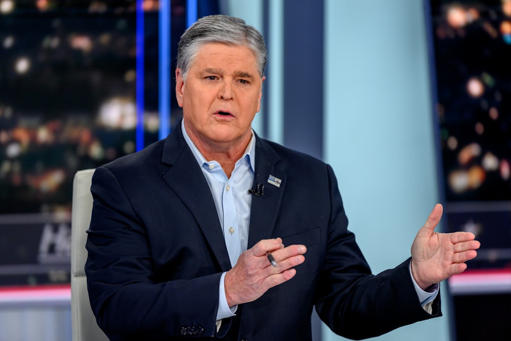 Sean Hannity gestures with both hands pointing to his left