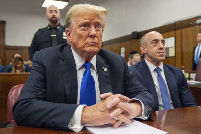 Donald Trump sits in a courtroom with his hands folded in front of him
