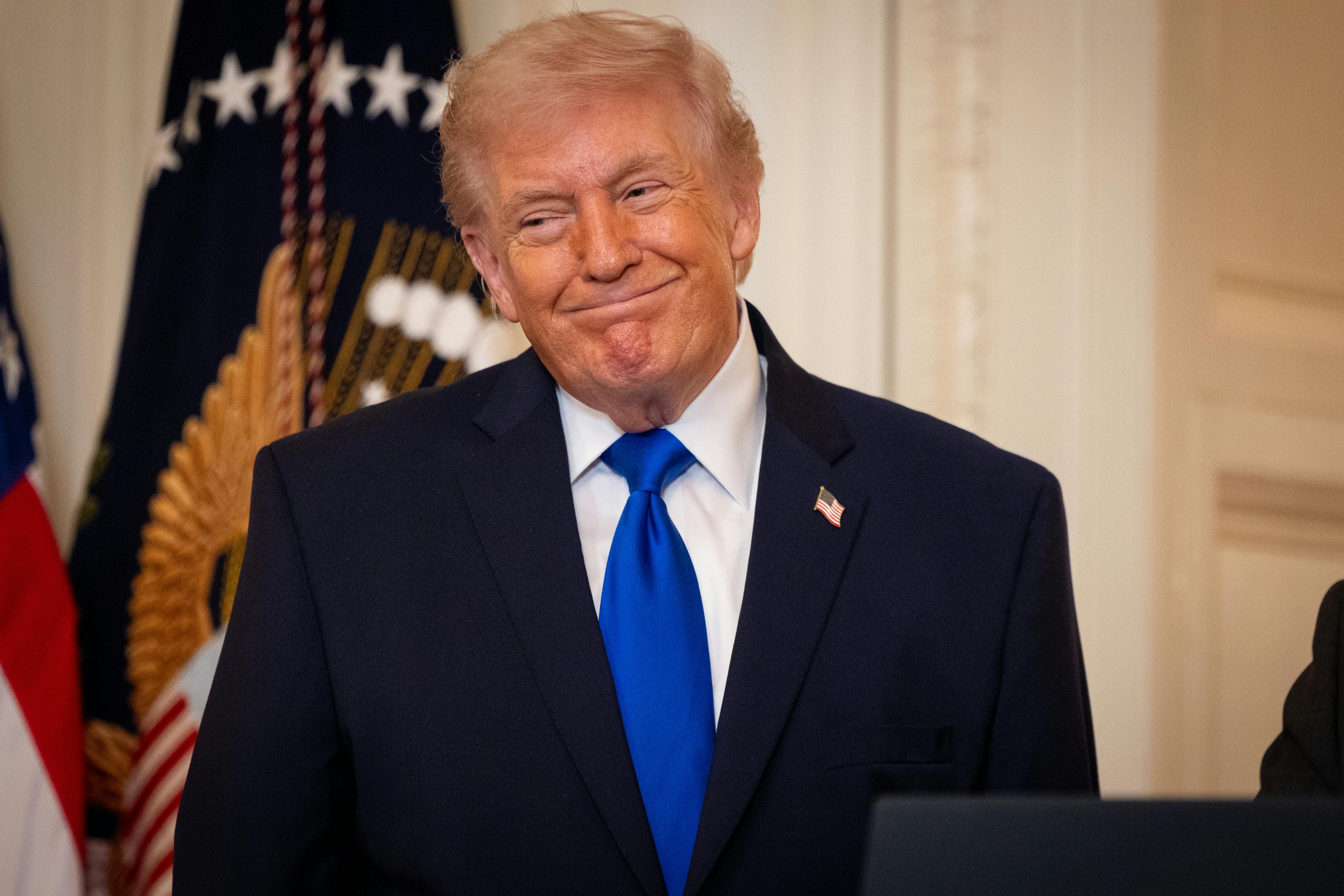 Donald Trump smiles while standing during an event