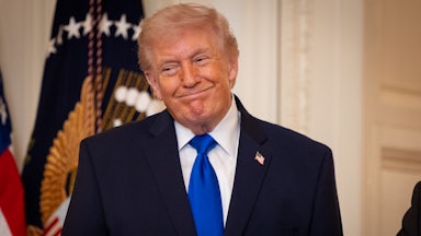 Donald Trump smiles while standing during an event