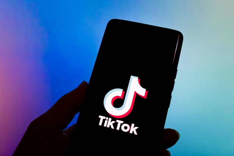 A person holds up a phone with TikTok open on the screen