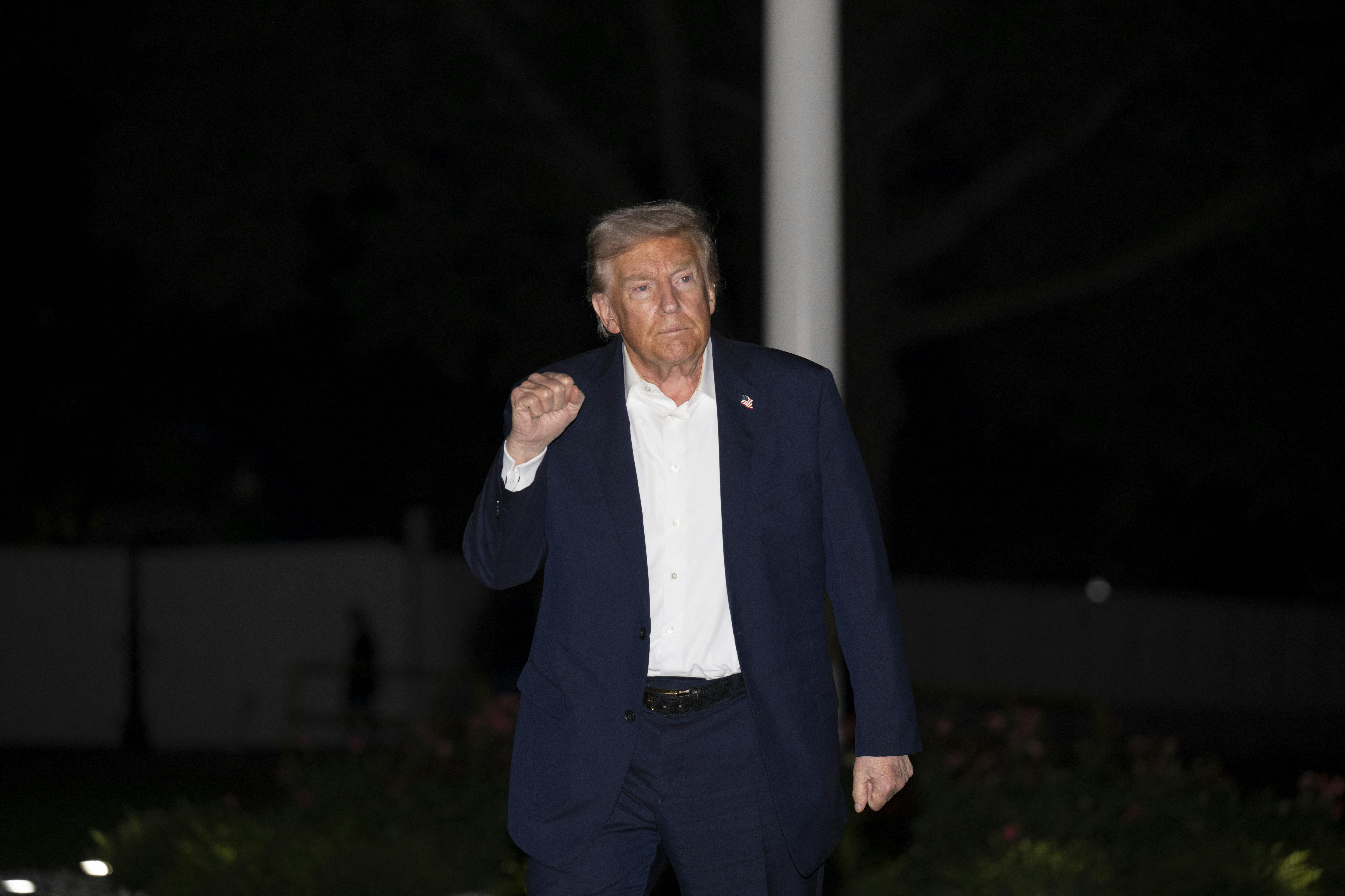 Donald Trump raises his fit while walking outside the White House
