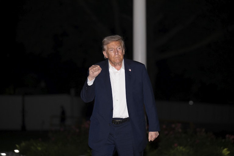 Donald Trump raises his fit while walking outside the White House