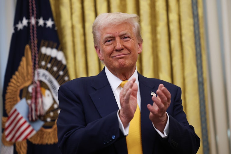 Donald Trump claps while standing in the White House