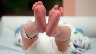 A pair of baby's feet, dangling in the air.