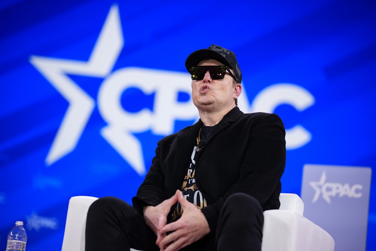 Elon Musk makes a face while seated onstage at CPAC