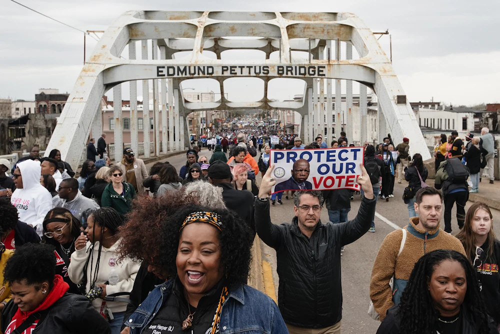 People march across the Edmund Pettus Bridge during commemorations of the 60th anniversary of “Bloody Sunday”