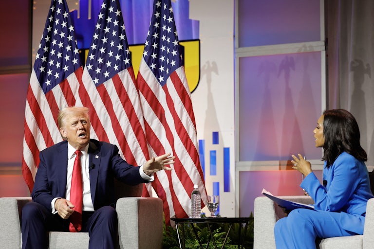 is sitted next to him. The two seem like they are in a heated conversation.