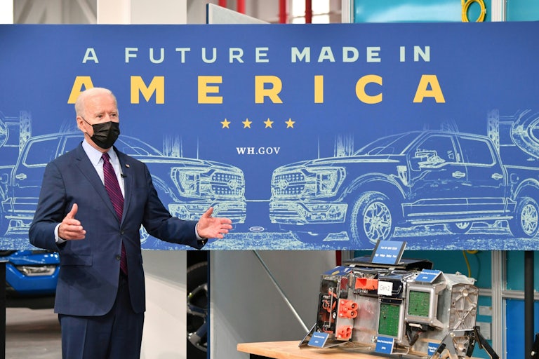 Biden stands in front of a table with electric vehicle parts.