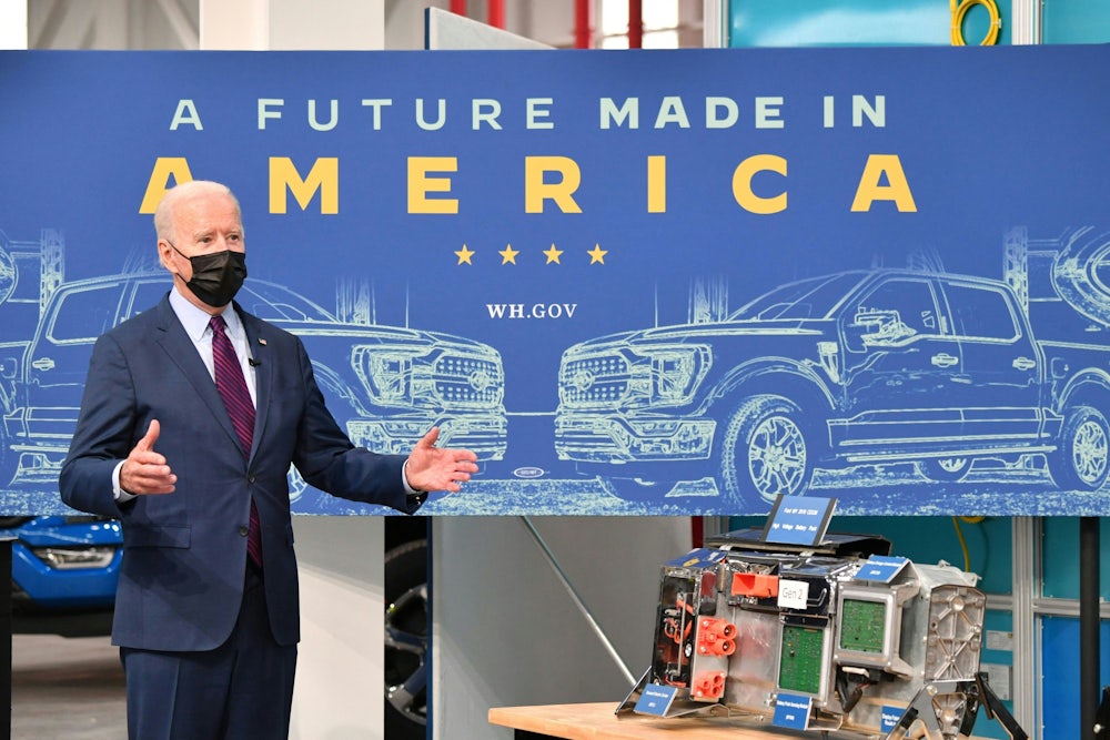 Biden stands in front of a table with electric vehicle parts.