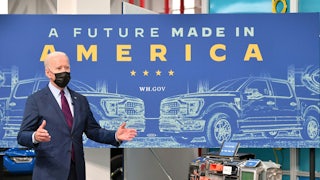 Biden stands in front of a table with electric vehicle parts.