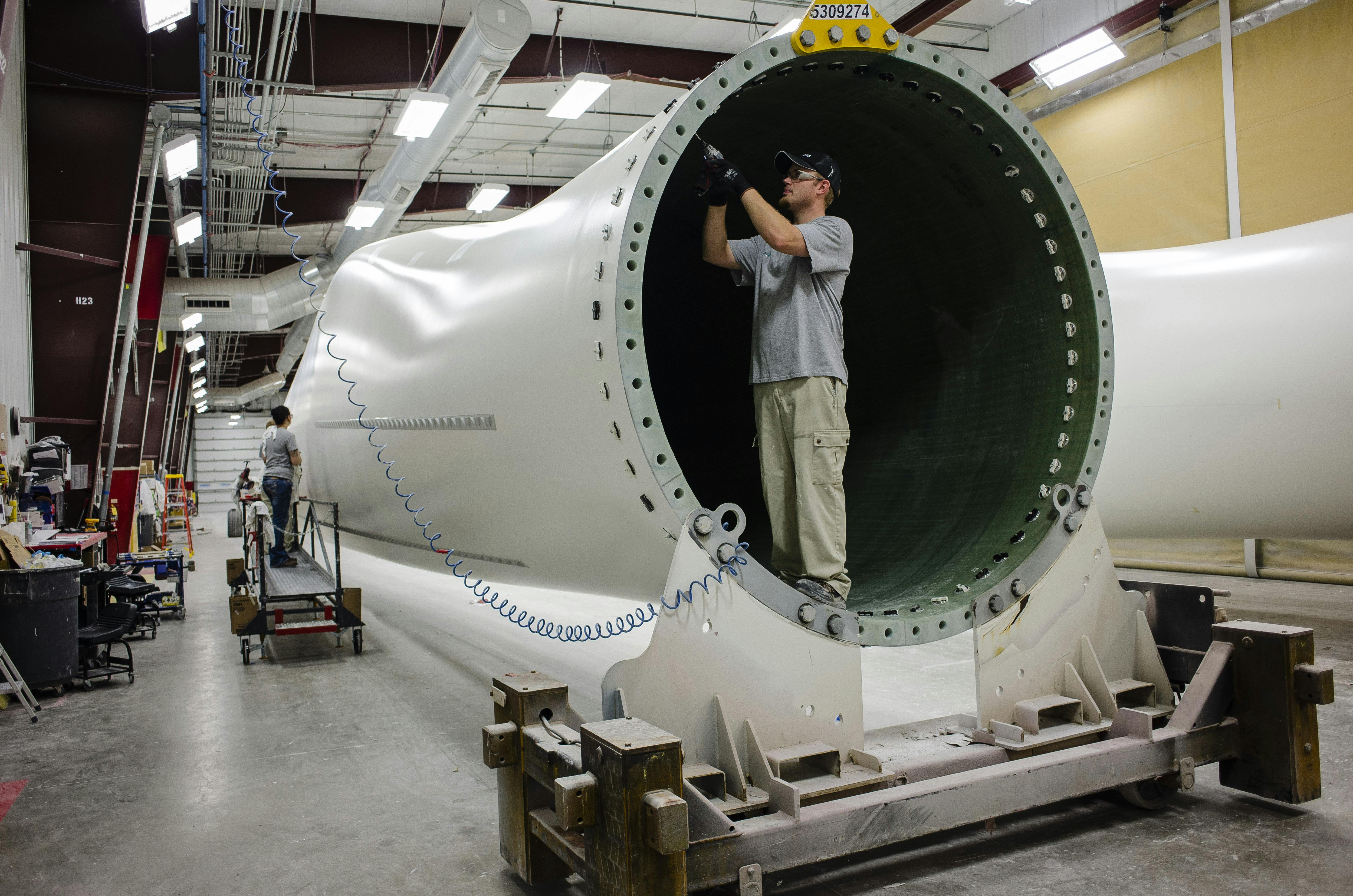 A worker installs components at the base of a wind turbine blade at the Siemens plant in Fort Madison, Iowa
