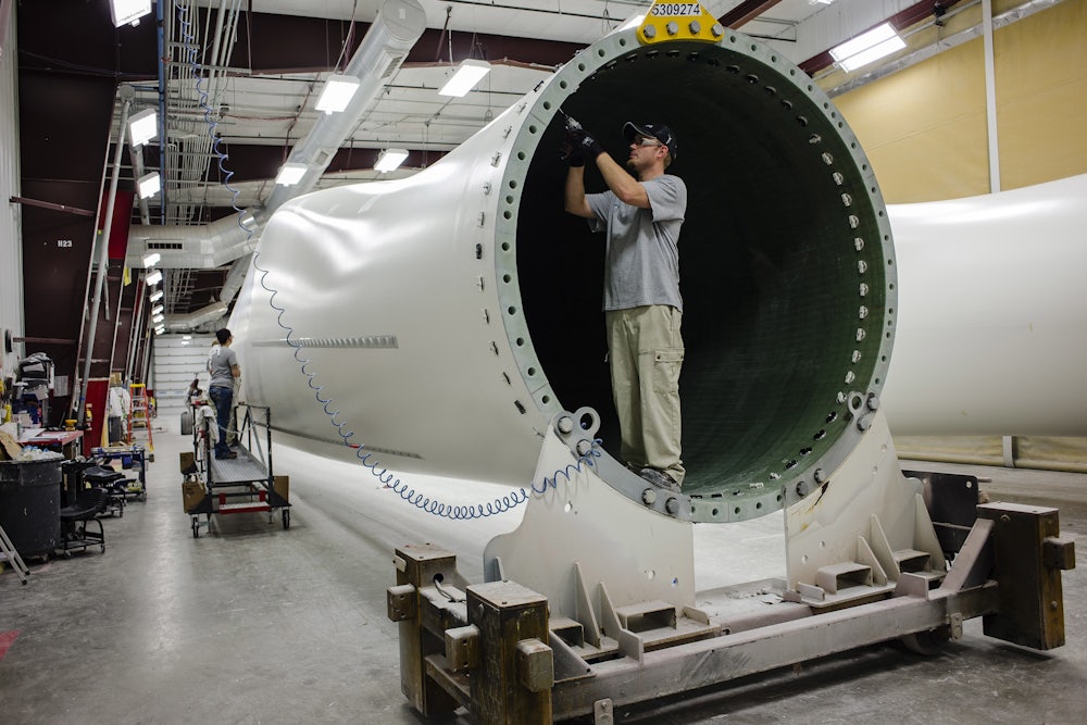 A worker installs components at the base of a wind turbine blade at the Siemens plant in Fort Madison, Iowa