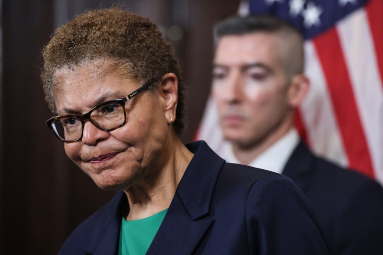 Karen Bass looks at the ground and scowls.