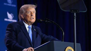 Donald Trump grimaces while standing at a podium
