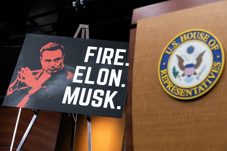 A sign calling to “fire Elon Musk” during a Congressional Progressive Caucus press conference