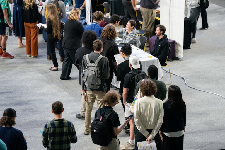 People stand in a line at a job fair.