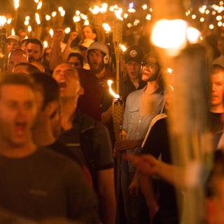 Young white men hold tiki torches and shout