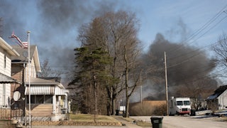 A plume of smoke rises over a residential neighborhood.