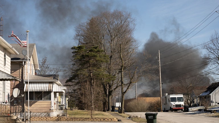 A plume of smoke rises over a residential neighborhood.