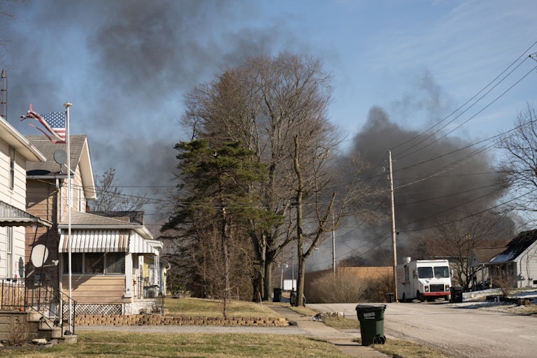 A plume of smoke rises over a residential neighborhood.