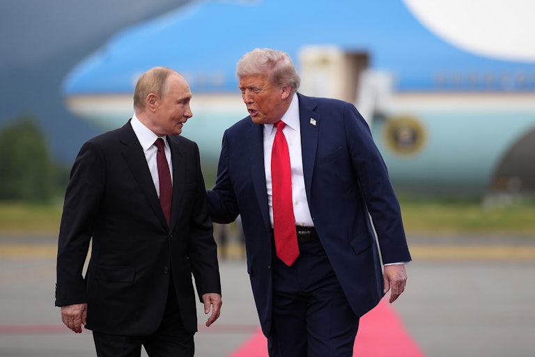 Donald Trump puts his hand on Vladimir Putin's shoulder and speaks as they walk on an airport tarmac