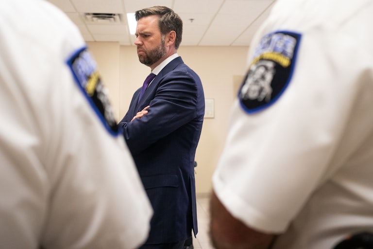 J.D. Vance stands with his arms crossed during a tour of a police station