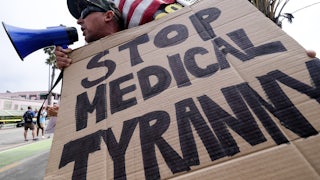 An anti-vaccination protester holds a sign and a flag as he takes part in a rally against Covid-19 vaccine mandates.