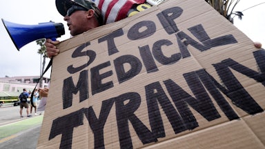 An anti-vaccination protester holds a sign and a flag as he takes part in a rally against Covid-19 vaccine mandates.